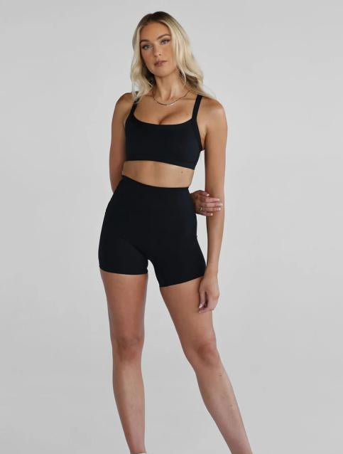 Woman wearing a black athletic outfit on a gray background